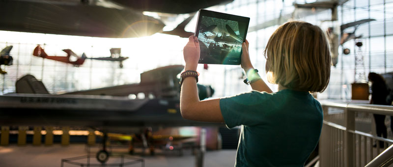 Child in an airline hangar looking at a tablet device