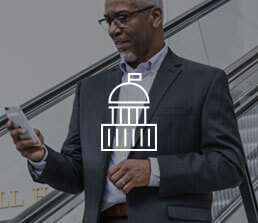 a man holding a phone with a government icon overlaid on the image.