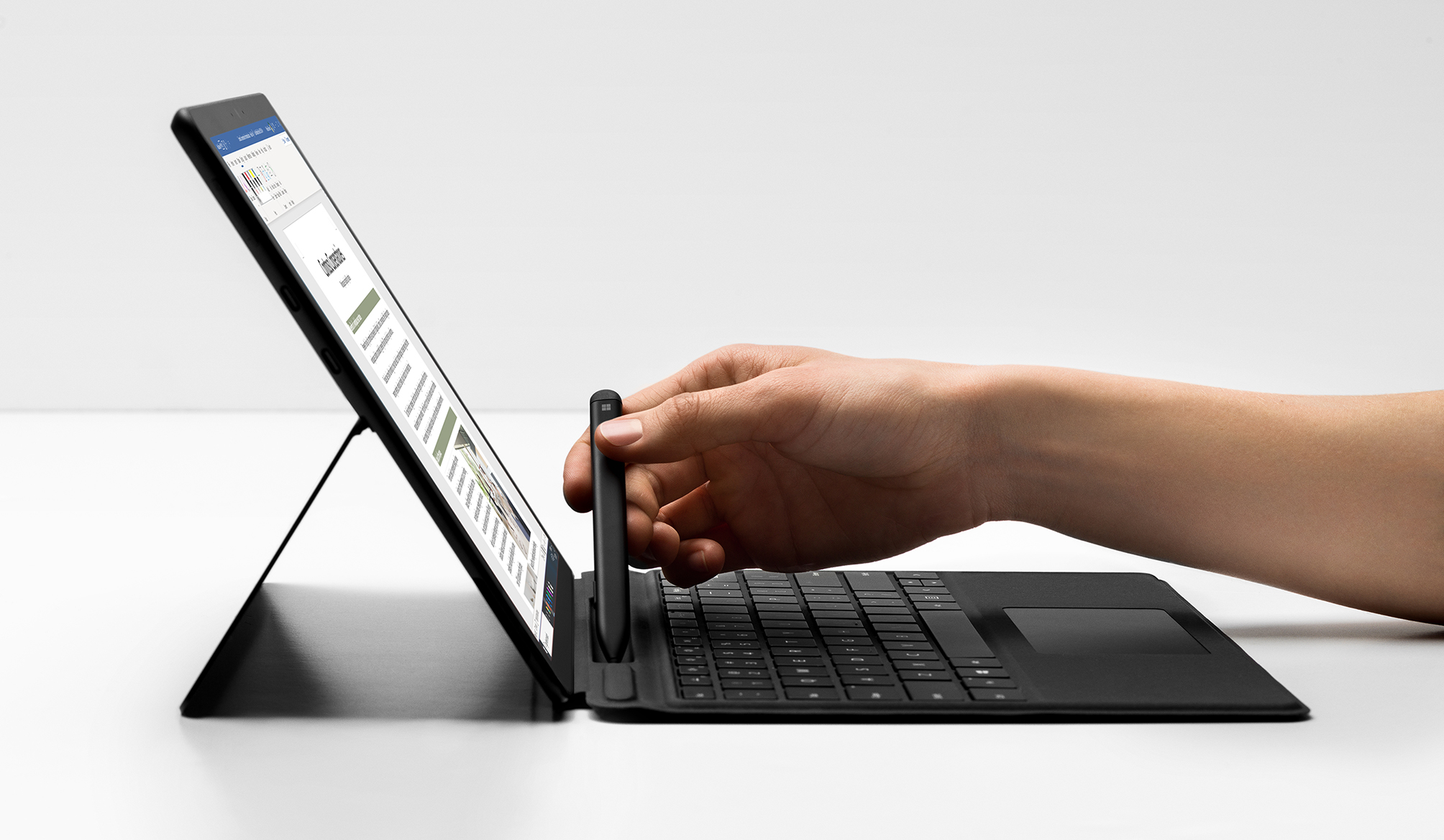 Abbildung einer Hand, die einen Stift aus dem Fach des neuen Surface Pro X nimmt