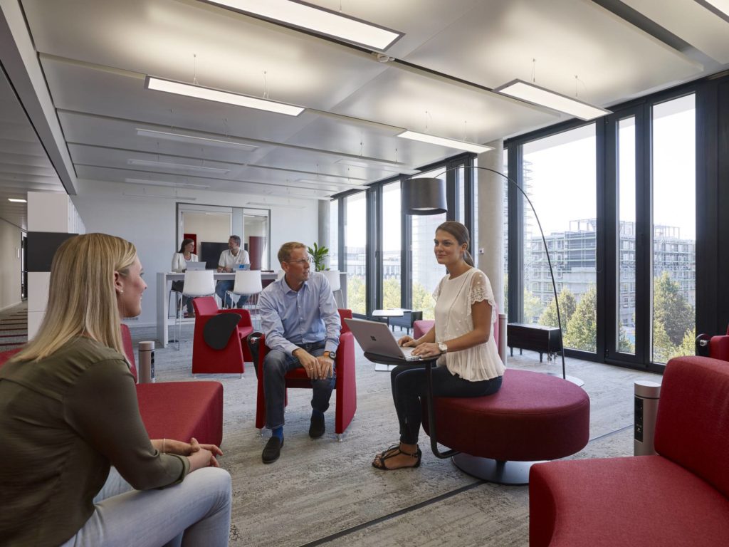 Drei Leute sitzen im Microsoft München Büro zusammen unterhalten sich über etwas.