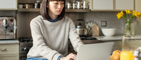 Eine Frau sitzt in der Küche und arbeitet an einem Surface Device