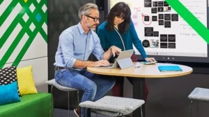 Eine Frau und ein Mann arbeiten zusammen an einem mobilen Device an einem modernen Arbeitsplatz