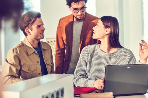 Drei junge Menschen diskutieren miteinander in einem Büro.