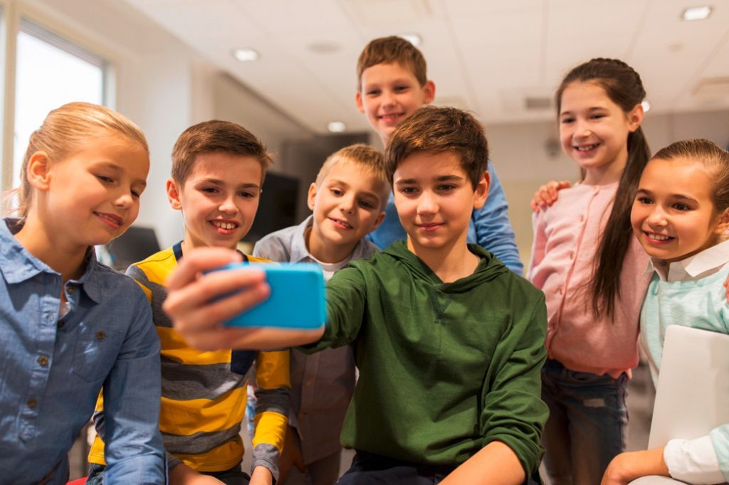 Eine kleine Gruppe von jungen Klassenkameraden macht ein Gruppen-Selfie mit dem Smartphone. Das Projekt Aura fördert den Einfluss der Schüler auf Ihre Schule.