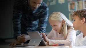 Ein Lehrer hilfe einer Schülerin beim Arbeiten an einem Surface Laptop