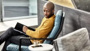 A man is using his Lenovo laptop like a tablet while sitting in a comfortable chair in a Modern office setting