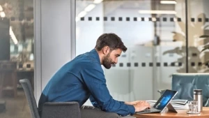 Ein Mann arbeitet mit einem Laptop auf einem Sofa und einem Beistelltisch