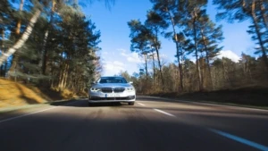 Ein BMW fährt auf einer Landstraße durch den Wald