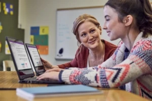 Eine Lehrerin und eine Schülerin arbeiten gemeinsam an zwei Surface Devices