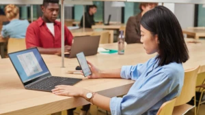 Eine Frau sitzt an einem Tisch und schaut in ihr Smartphone