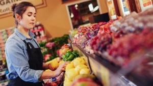 Eine Verkäuferin in einem Supermarkt in der Gemüseabteilung
