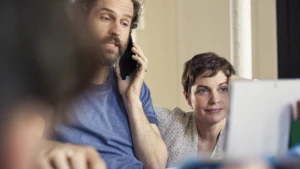 Vater und Mutter in der Küche mit Telefon und Laptop.