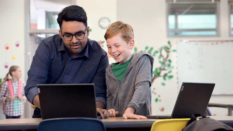 Mann hilft männlichem Studenten auf einem Laptop.
