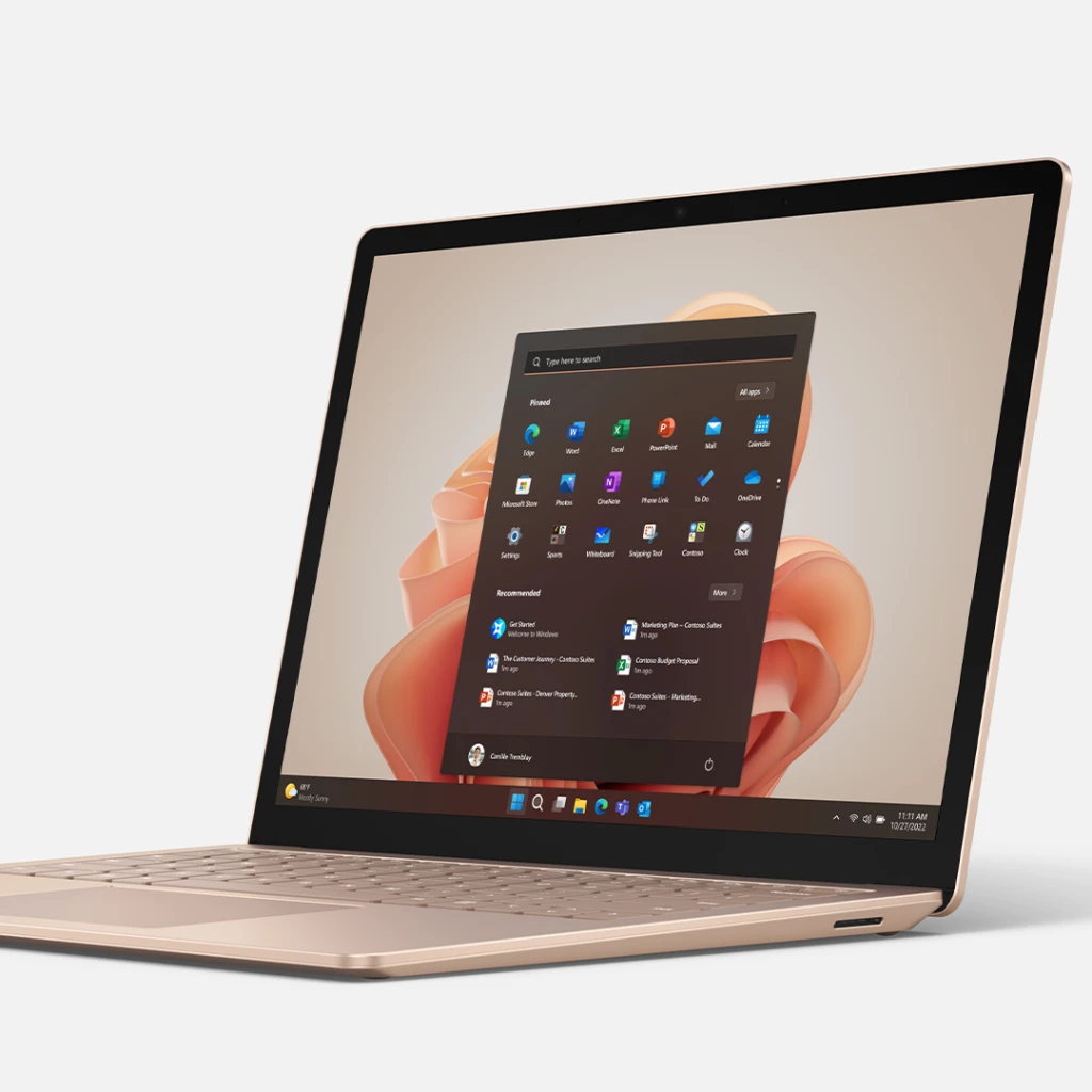 Auf dem Bild ist das Surface Laptop 5 in Sandstein-Optik zu sehen. Der Laptop ist aufgeklappt und auf dem Desktop ist der Homescreen zu sehen.