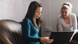 Junge Dame sitzt und arbeitet an ihrem Laptop