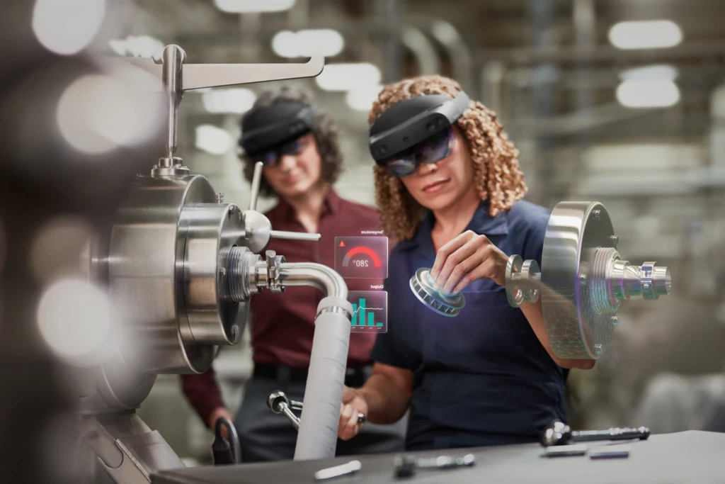 Zwei Frauen in einer Fertigungsanlage mit Microsoft Hololens 2 für die Montage. Enthält ein Hologramm-Szenario. Enthält ein Hologramm. Kontextuelles Bildmaterial.