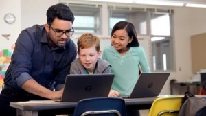 Ein Lehrer, ein Junge und ein Mädchen schauen gemeinsam auf einen Laptop