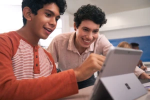 Eine Lehrerin zeigt einem Schüler etwas an seinem Tablet PC