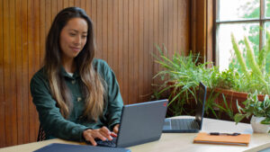 Eine junge Frau sitzt am Laptop.