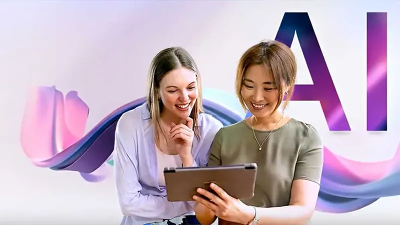 Zwei Frauen mit Tablet PC vor pastellfarbenem Hintergrund, auf dem halb verdeckt von den Frauen in großen Lettern das Kürzel "AI " steht.