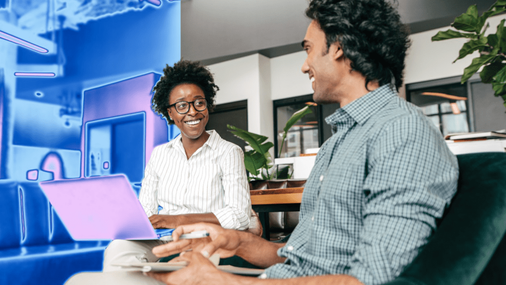 A man and woman sitting in a chair looking at a laptop.
