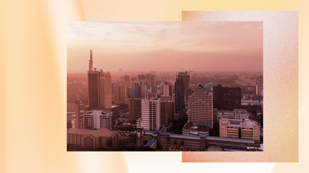 A cityscape featuring tall buildings and skyscrapers under a warm, orange-pink sky, suggesting either sunrise or sunset.