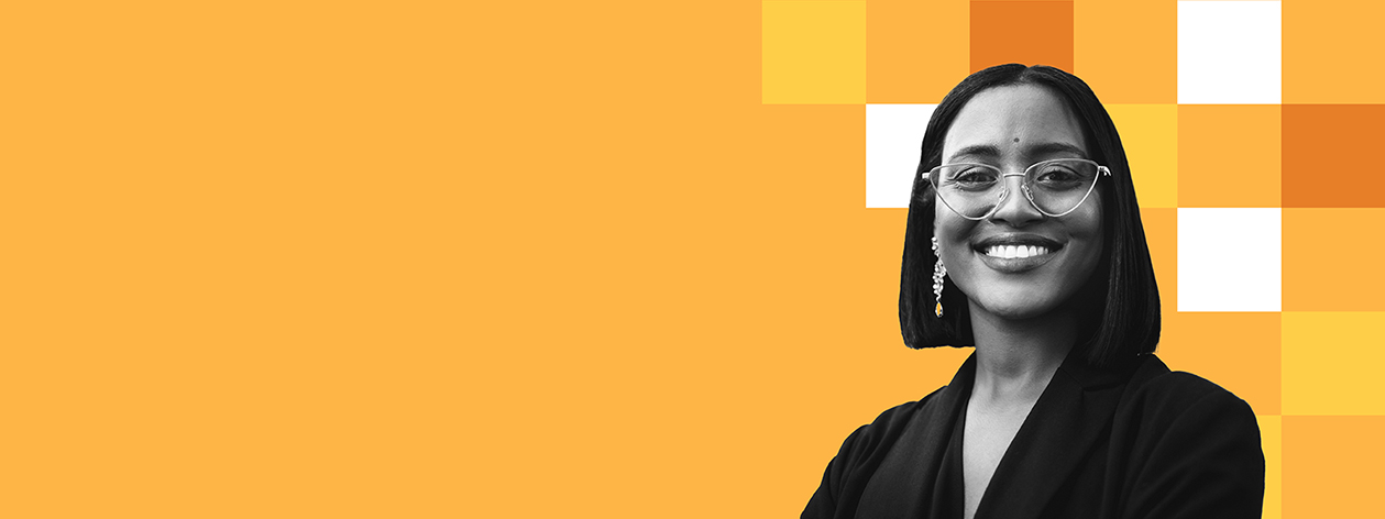 A smiling woman in black, wearing glasses and long dangle earrings, against a vibrant orange and yellow checkered background.