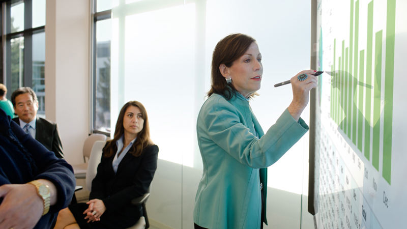 People in business attire going over numbers in a meeting using the Surface Hub.