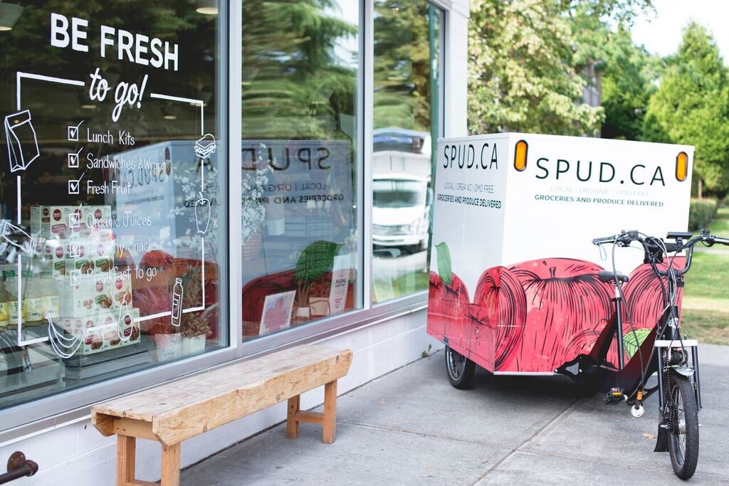 Photograph of a SPUD delivery ebike parked next to a Be Fresh retail store