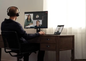 Teams call with headphones at a home desk on a Lenovo ThinkPad X1 Carbon.