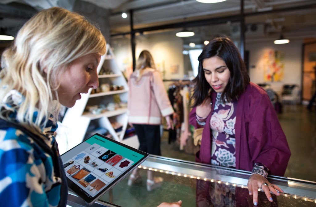 A women uses a Surface tablet and AI to help a female customer in a small SMB boutique retail shop.