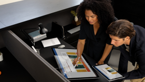 Man and woman collaborating in office with Surface Pro 6 and Surface Studio 2