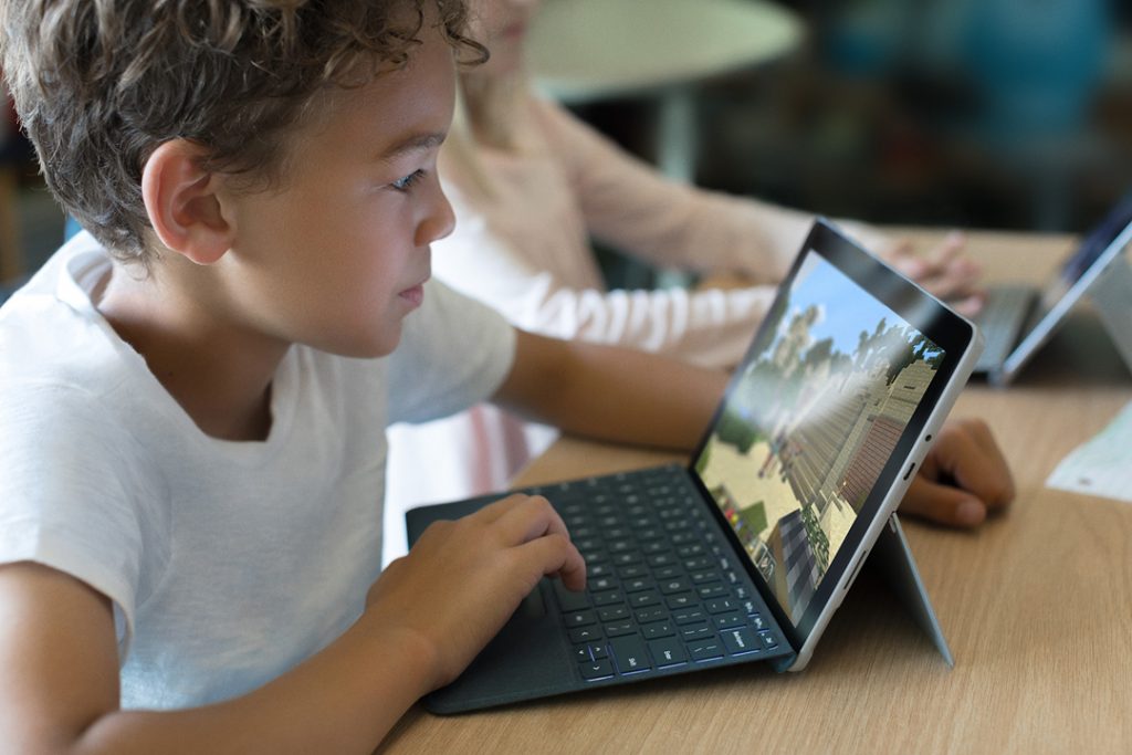 A young boy plays with Minecraft on a Surface Go in the classroom