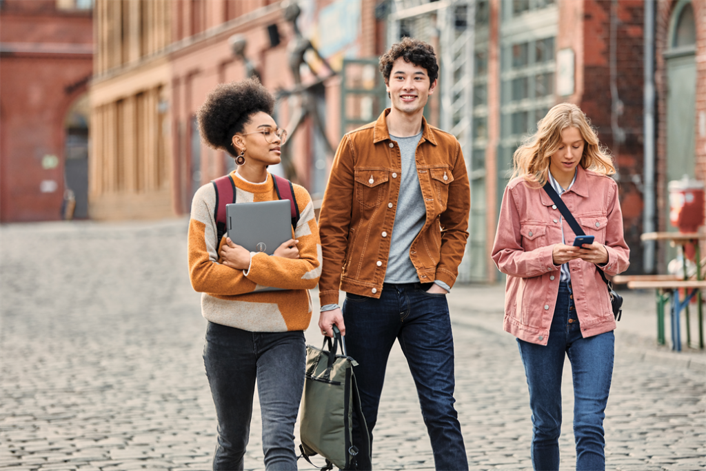 Two female and one male student on the go walking outdoors