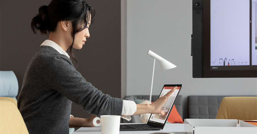 Contextual image of woman touching screen while working on Black Surface Laptop 2 inside at desk