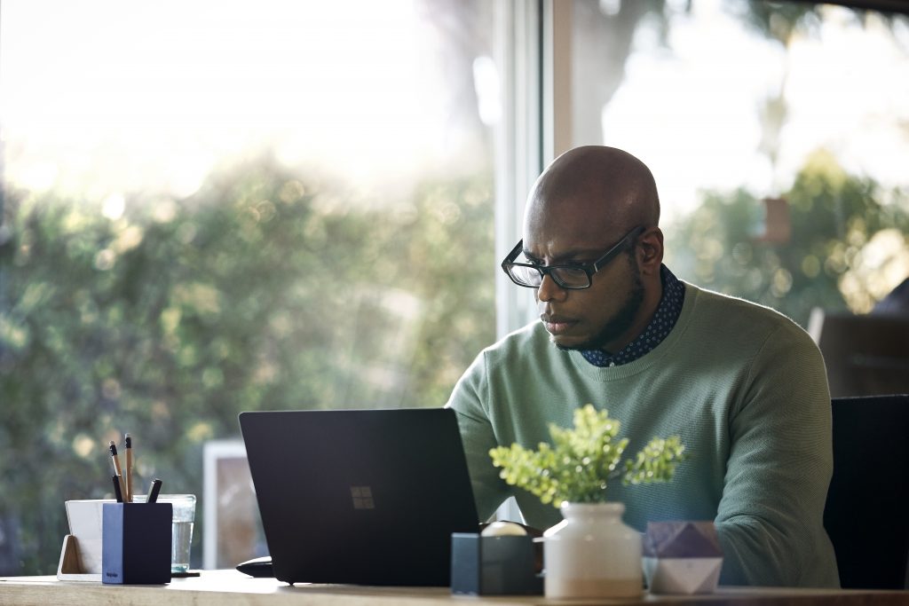 Male working remotely from his home office on Surface Laptop 2 device.