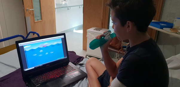 Child undergoes gamified cystic fibrosis treatment using laptop