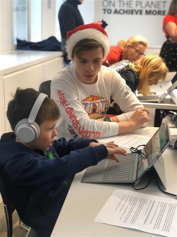 Child wearing Surface headphones and using a Surface with the help of a Microsoft employee