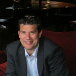 A man smiling at the camera in a business suit.