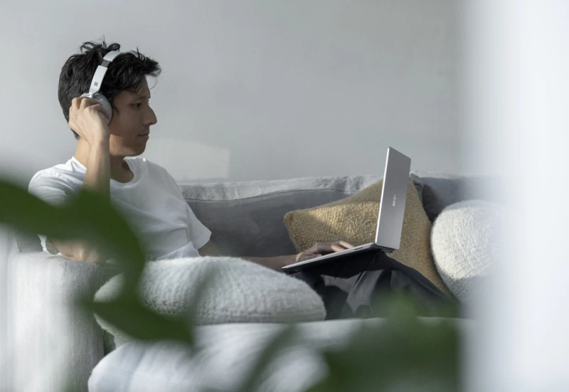 a man wearing headphones looking at a Surface laptop