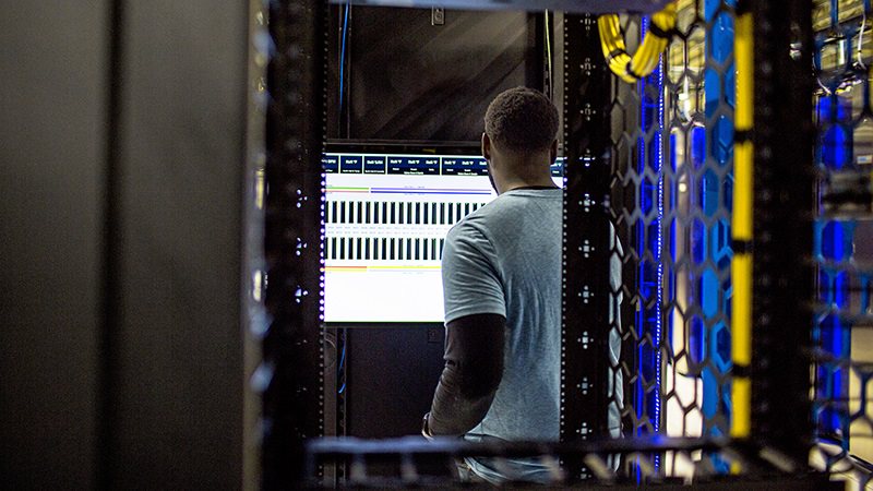An image of a man working on the screen in a data center