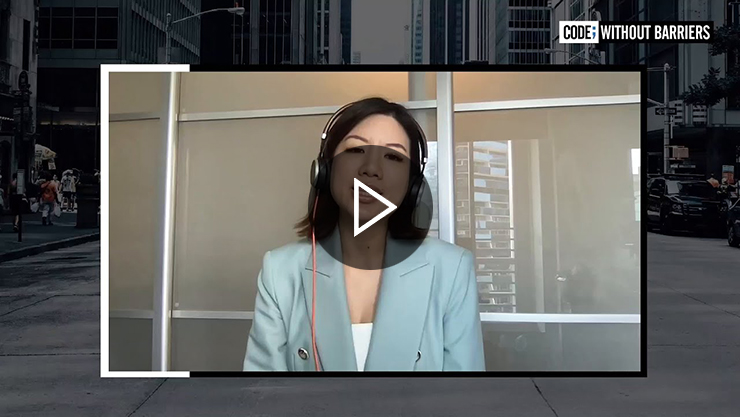 A person wearing headphones and a light blue jacket, seated indoors, with the text “Code; Without Barriers” displayed in the corner.