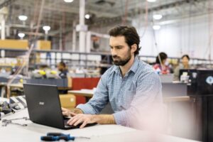 Male first line worker sitting at workstation in commercial manufacturing plant.