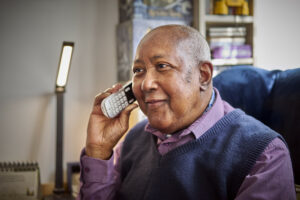 An older gentleman holds a phone to his ear.