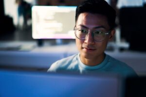 A person sitting at a desk and looking at a computer screen.