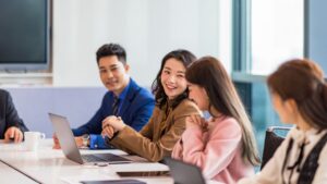 A group of smiling businesspeople collaborate in a meeting room.