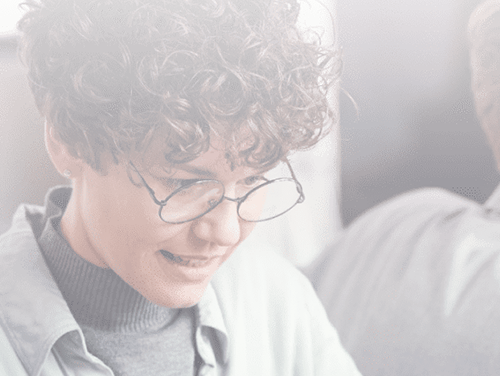 A woman with curly hair and glasses is staring down