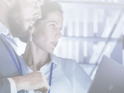 Two experts, one male and one female, strap on and together scrutinize the laptop screen.