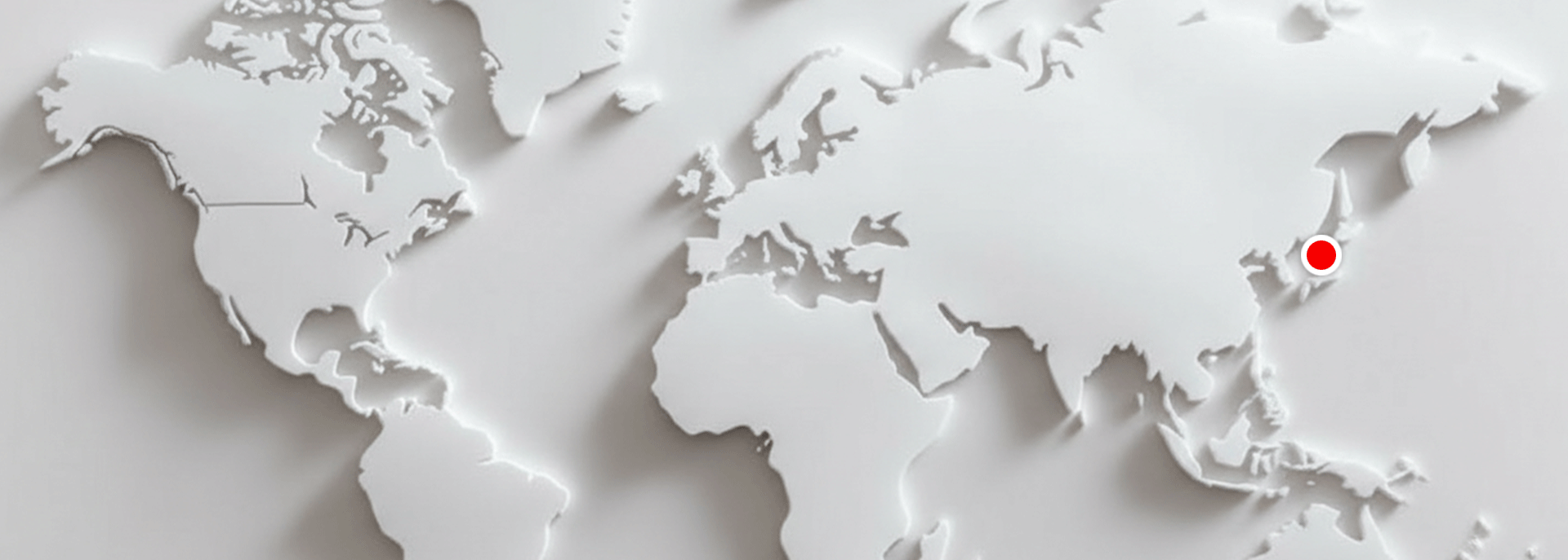 Minimalist 3D white world map with raised continents and subtle shadows; a red dot pulses in East Asia to indicate and label Kobe, Japan.