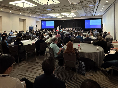 A diverse group of attendees sitting at tables in a conference room.